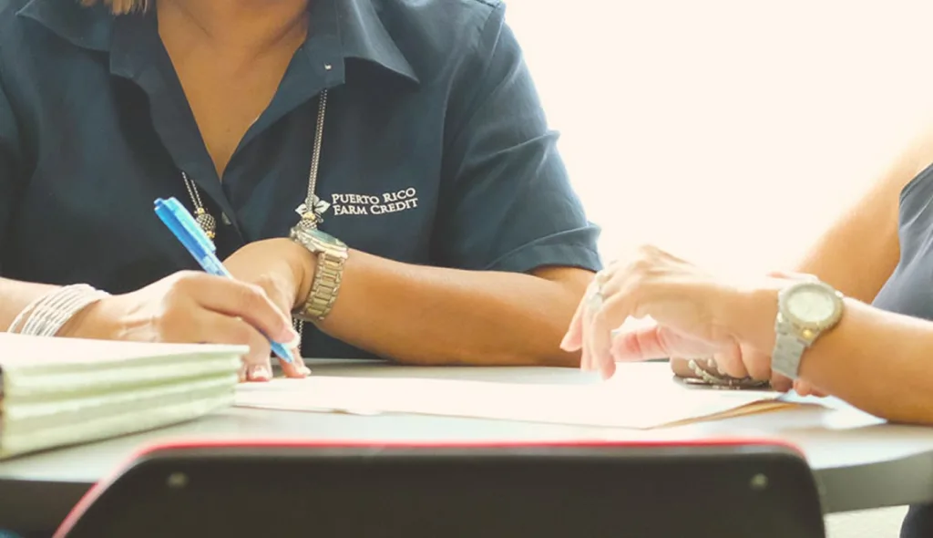 Personal de Puerto Rico Farm Credit firmando documentos de financiamiento, ilustrando el liderazgo y la asesoría del equipo.