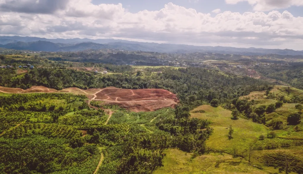 Paisaje aéreo de colinas y bosques en San Juan, Puerto Rico, con tierras despejadas para la agricultura, ilustrando el financiamiento de bienes raíces agrícolas.